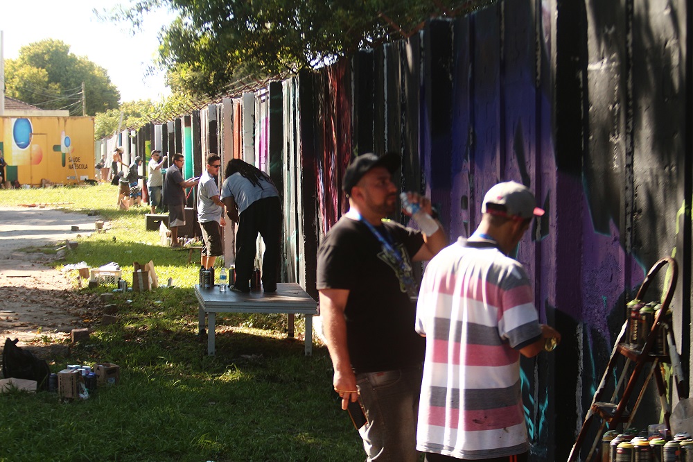 artistas trabalham no muro do Campus